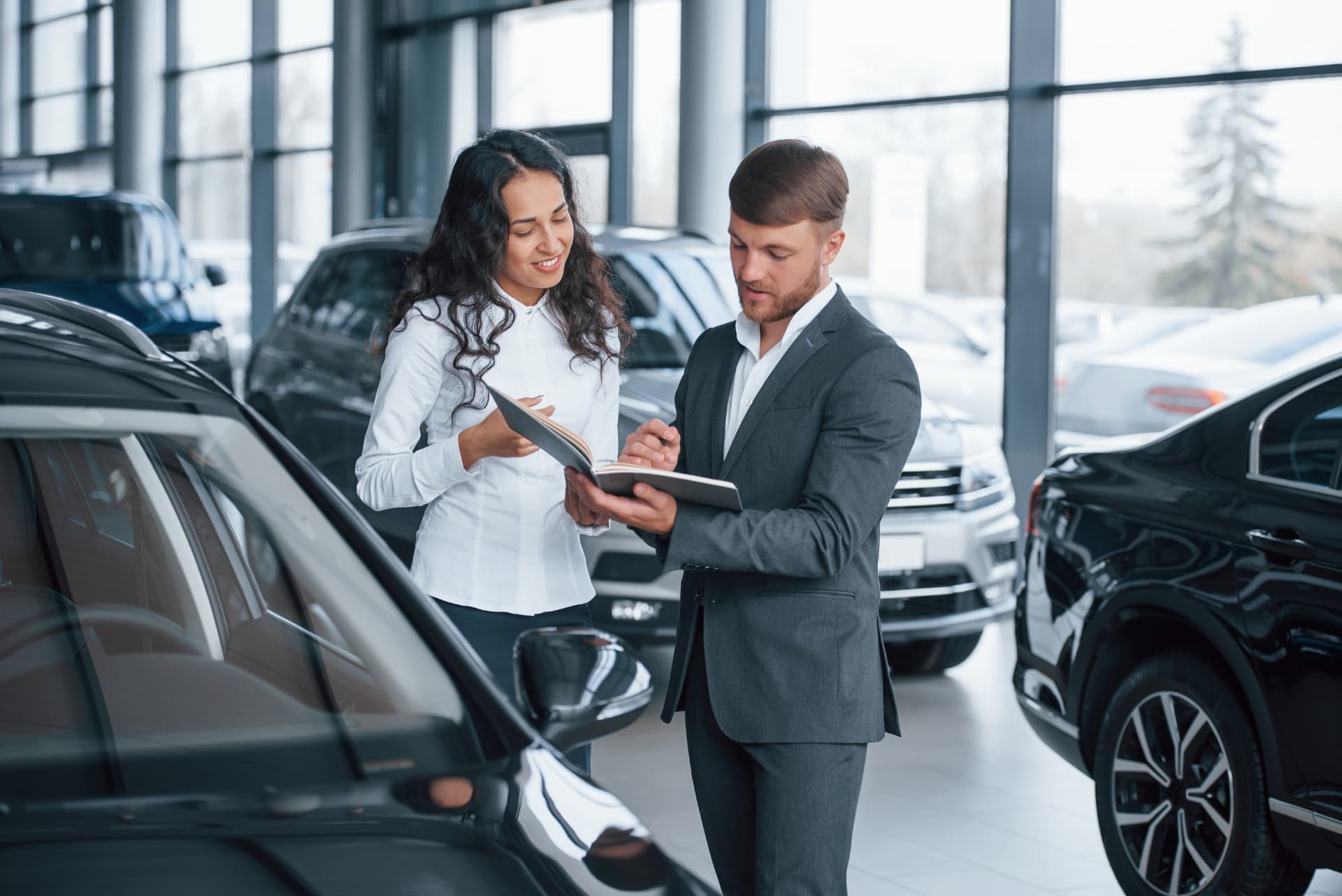 Sales advisor and customer in a dealership showroom — service retention begins with the customer experience